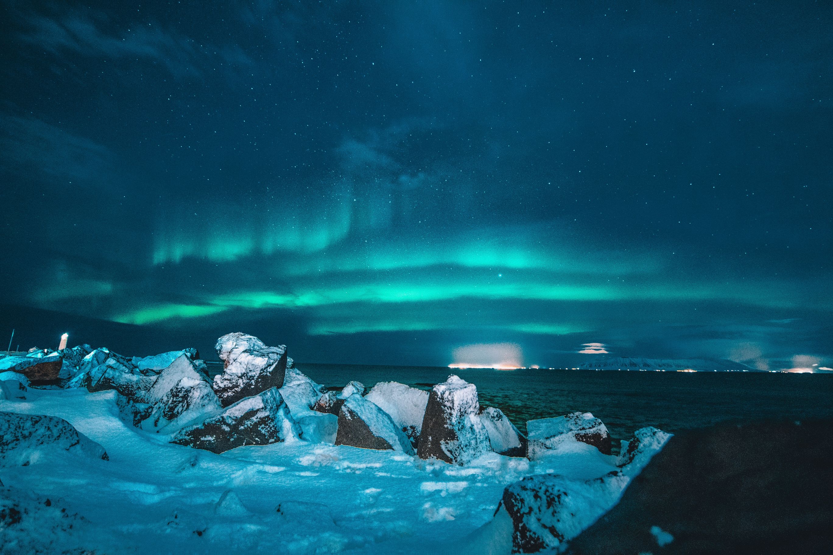 The northern lights above snow covered rocks.