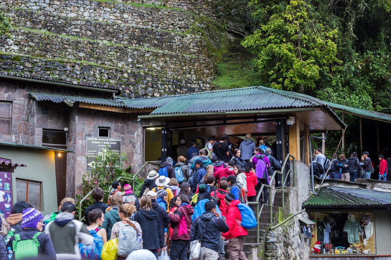 Crowds of tourists from all around the world waiting in long line in front of the entrance to the most known Inca landmark in Peru – Machu Picchu.