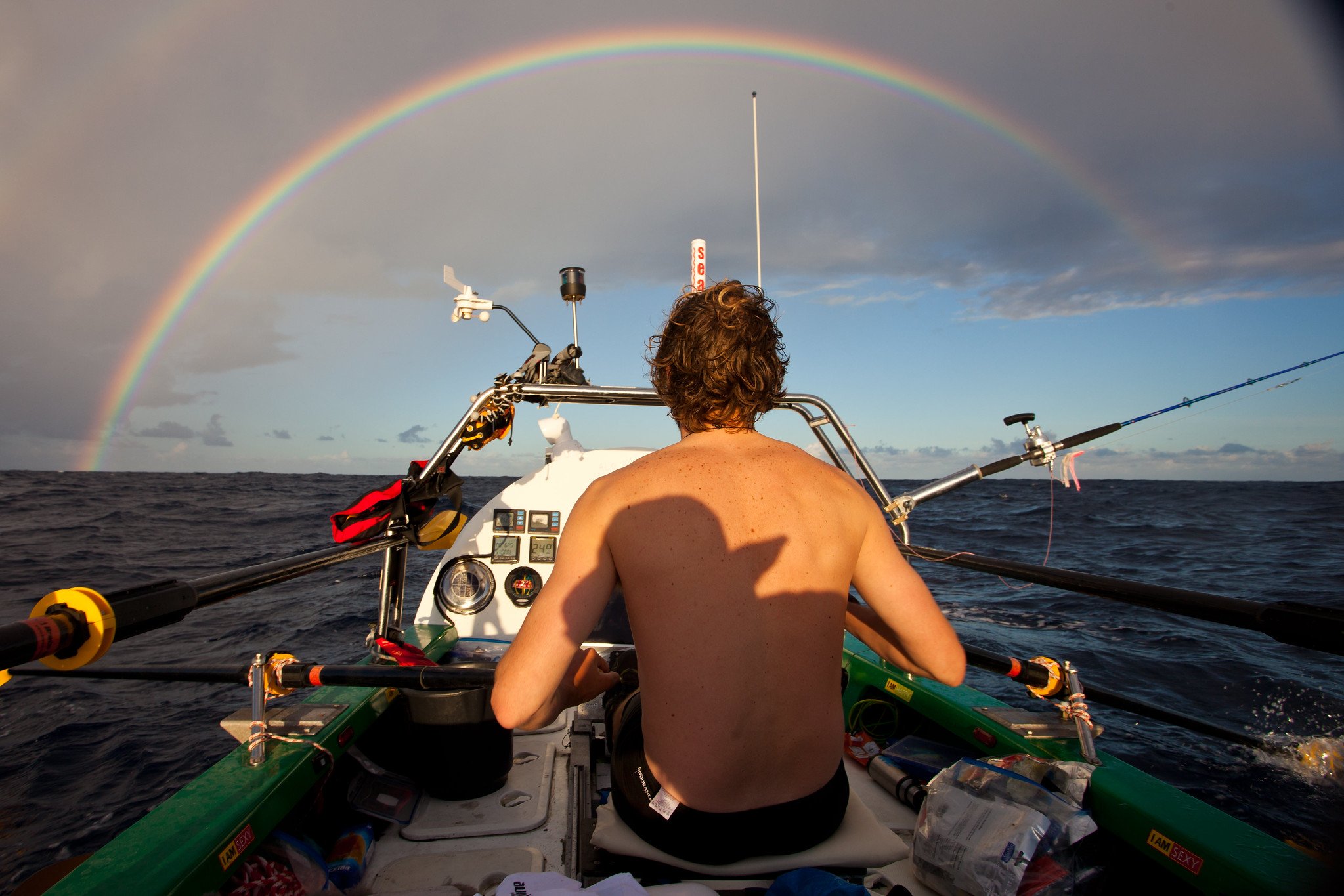 Alistair Humphreys rowing across the Atlantic Ocean, with a rainbow in front of him.