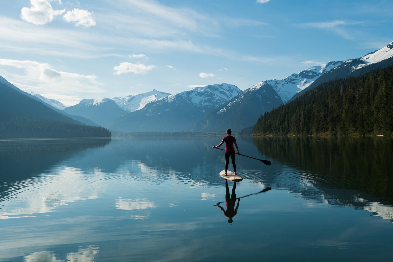 Woman stand up paddle boarding on a pristine mountain lake in British Columbia