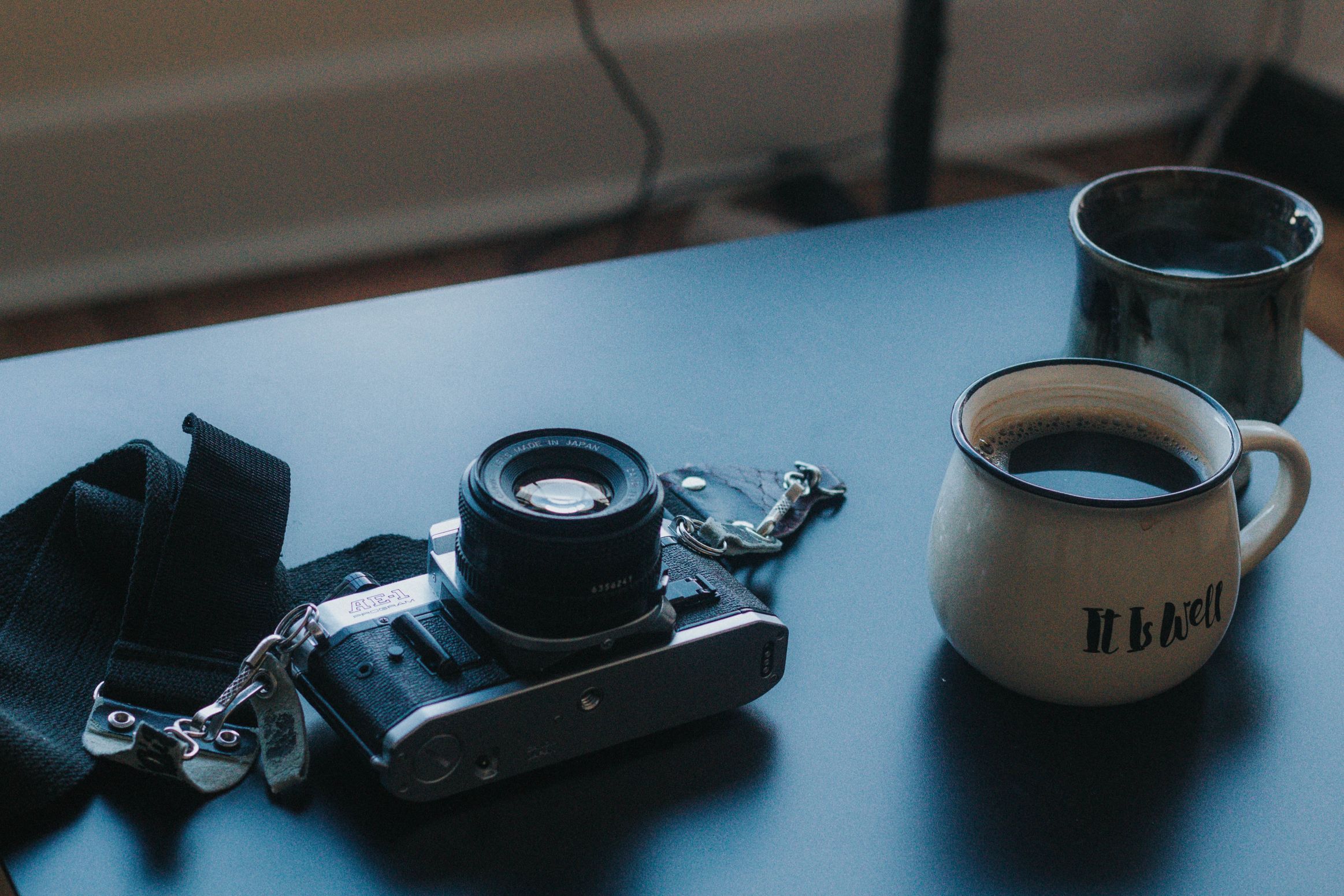 A film camera and a cup of black coffee on a table.