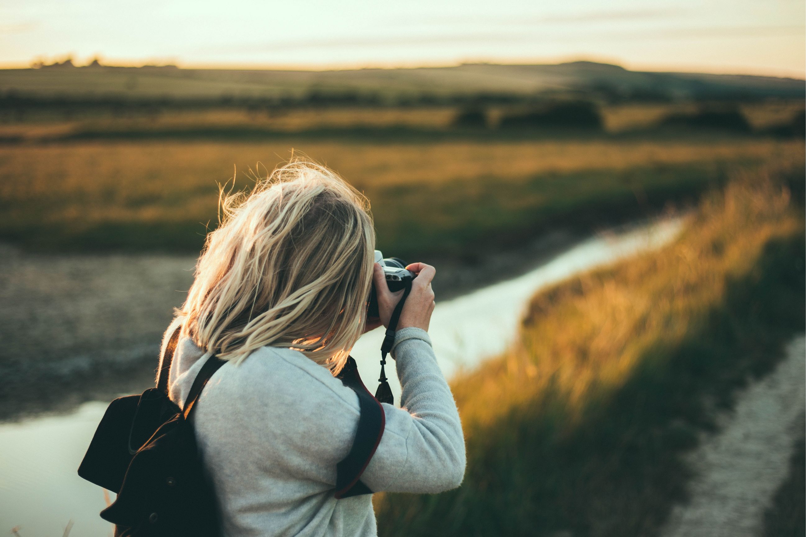 A hiker photographing the Cuckmere Valley at sunset.