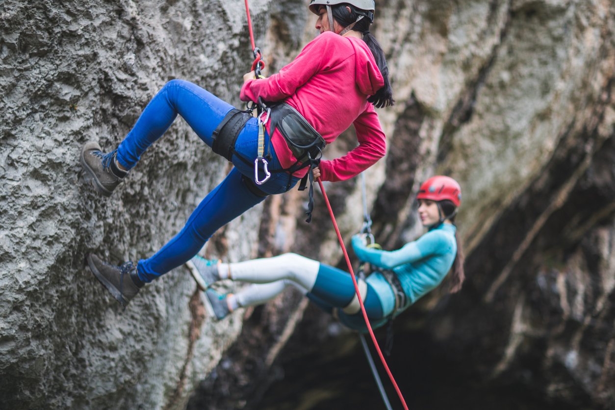 Female climbers abseiling down a crag.