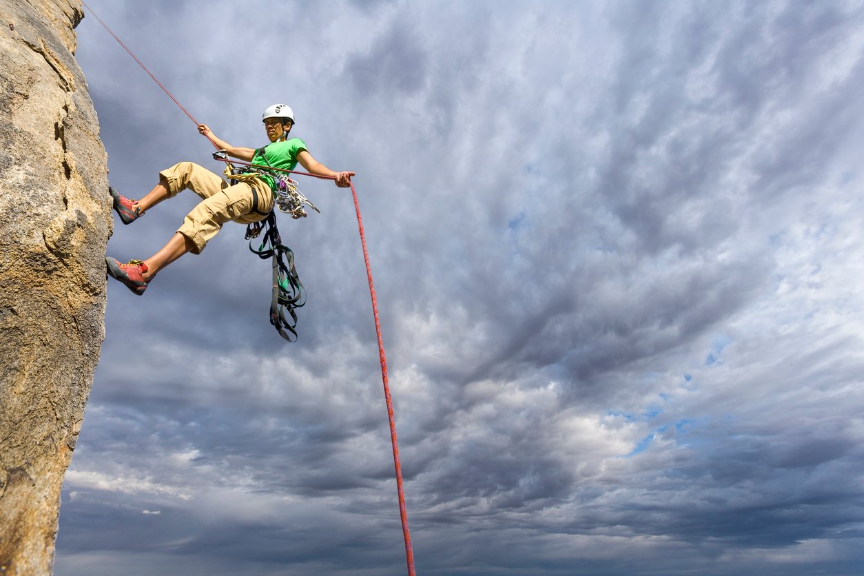 A climber abseiling down a sheer rock face.