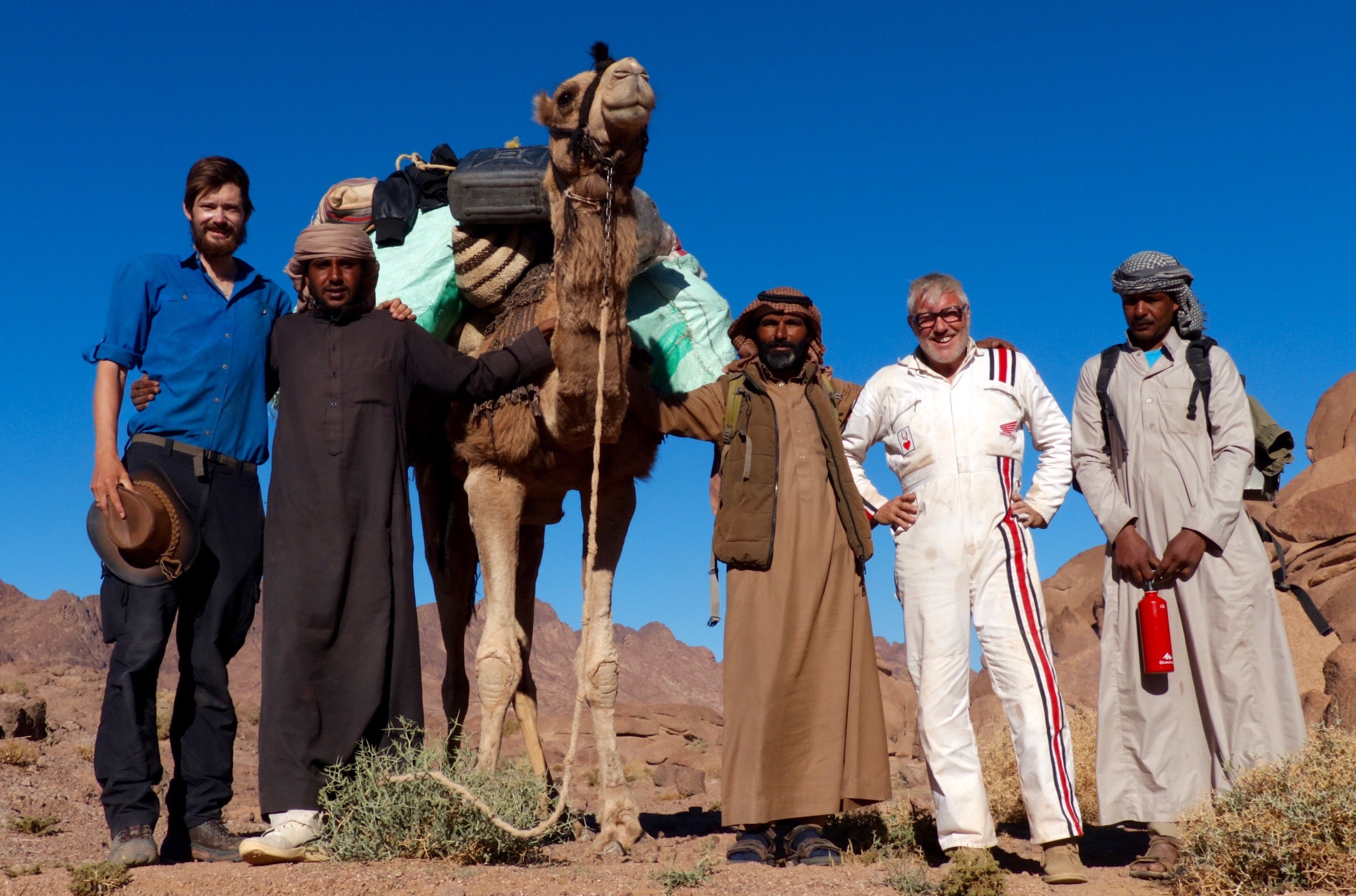 A group pose with a camel in the desert of Jordan.
