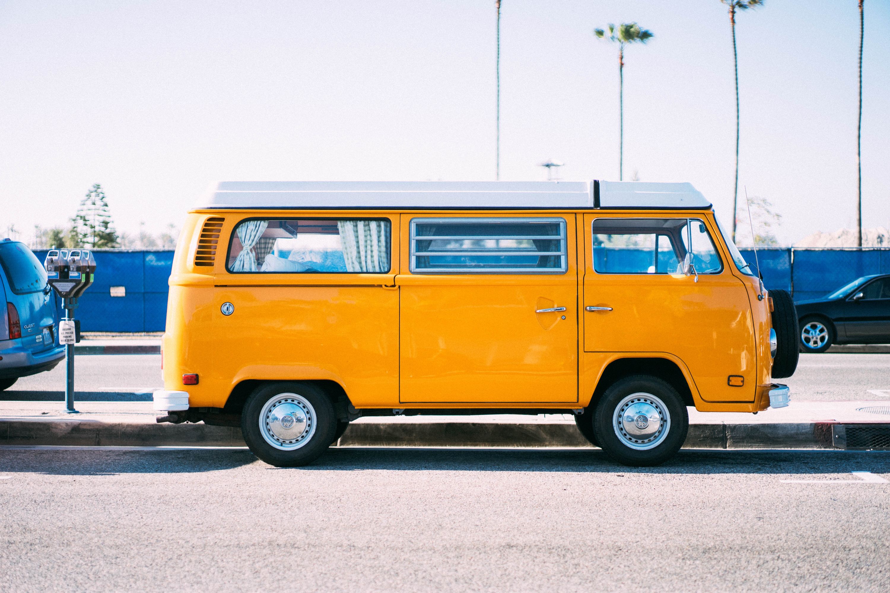 A picture of a yellow camper van parked on the side of the road.