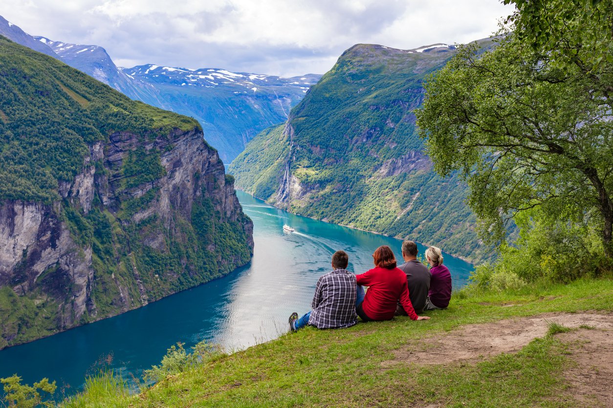 Travellers sitting on the ground and looking at the Geirangerfjord, Norway