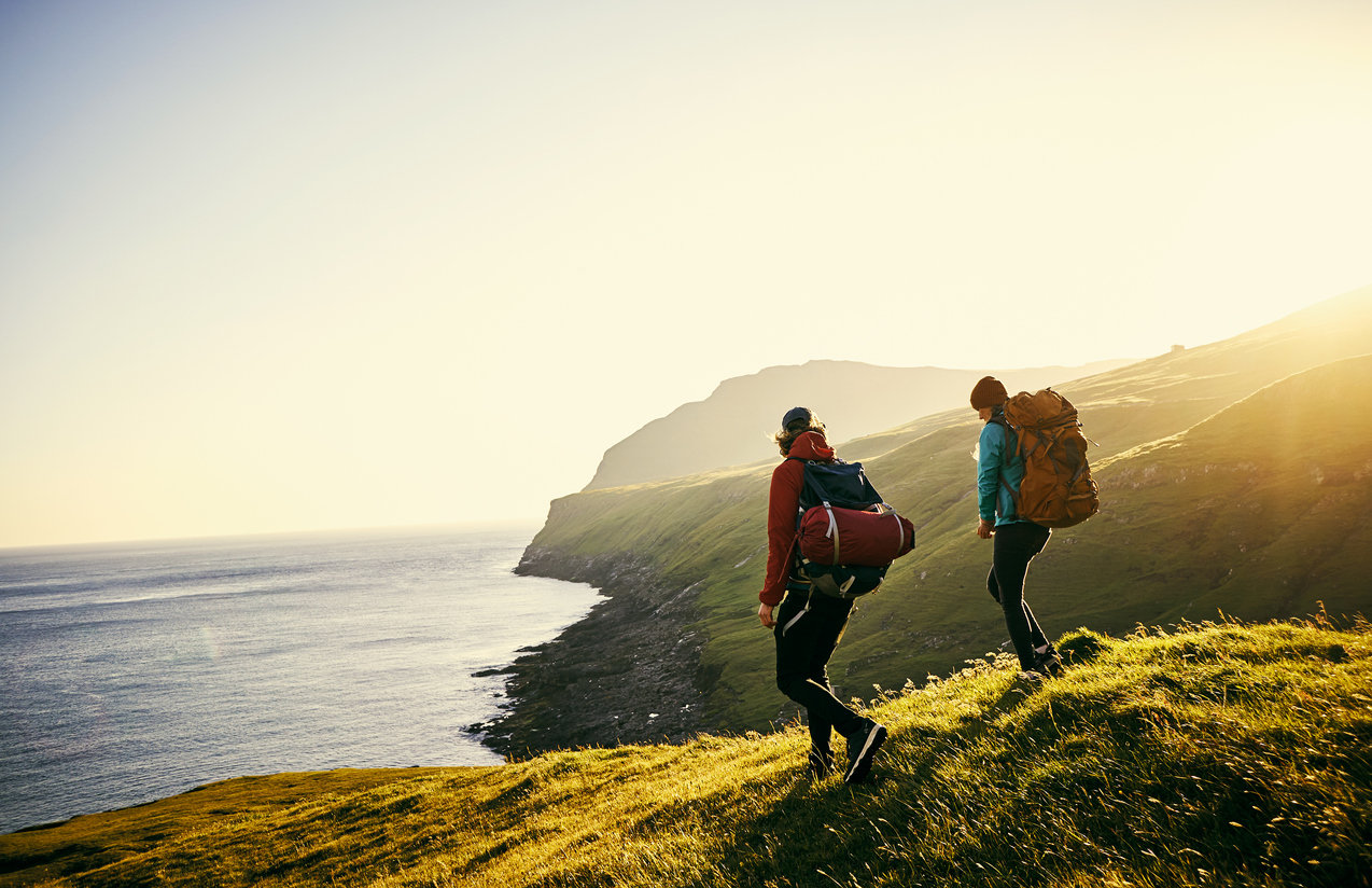 Two hikers walking by the coast.