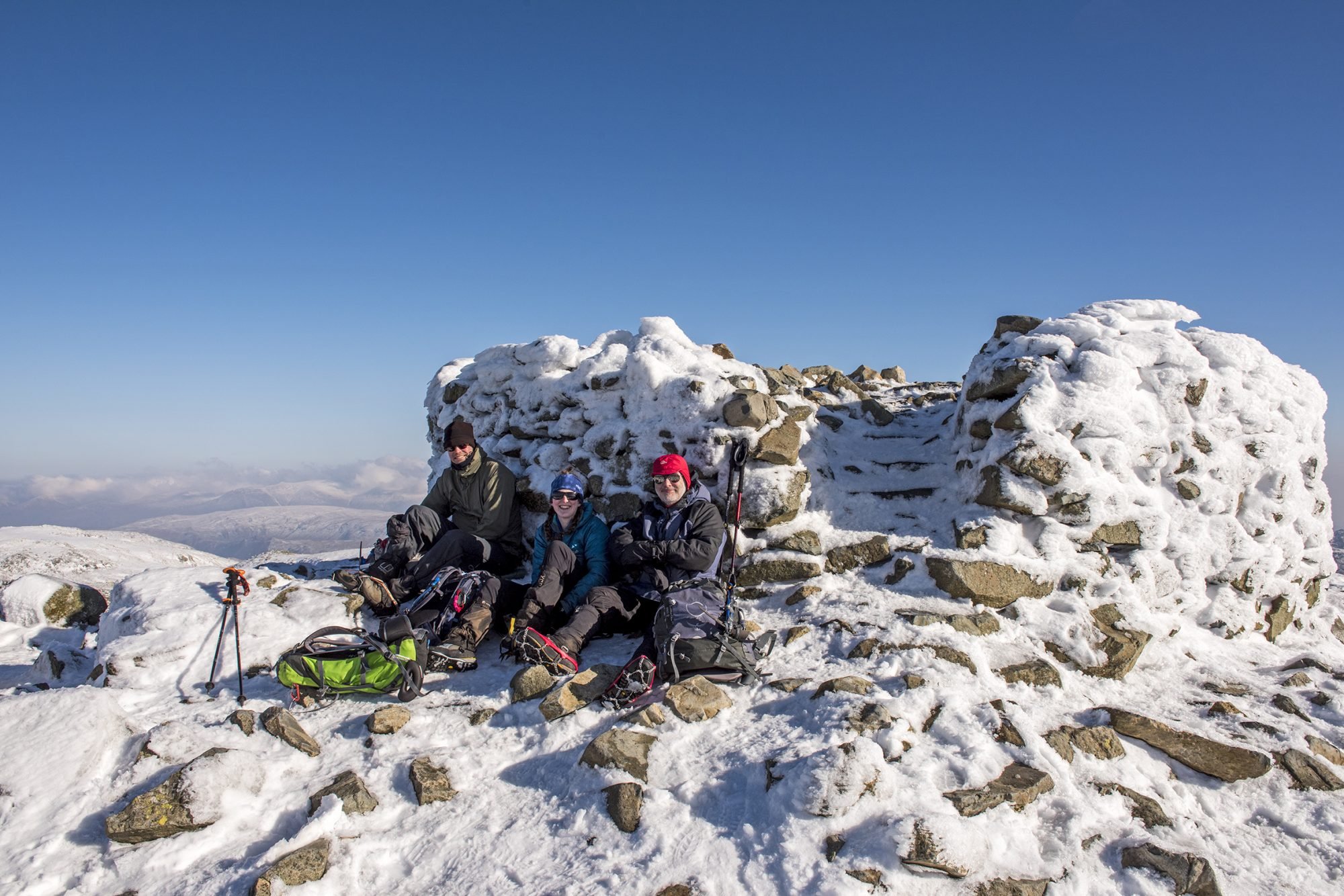 Hikers arrive at the top of Scafell Pike in winter, stop one of the three peak challenge