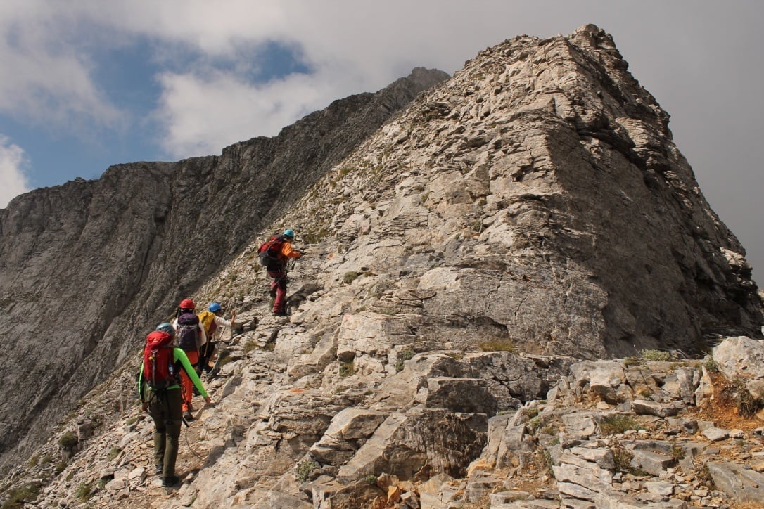 Climbers scrambling up to the exposed summit of Mount Olympus