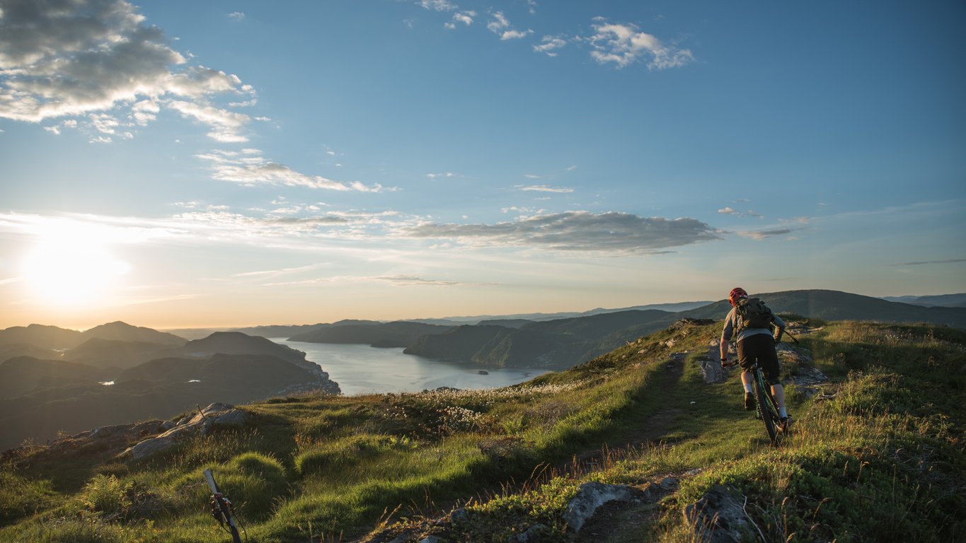 A man mountain biking down towards a fjord outside Bergen in Norway