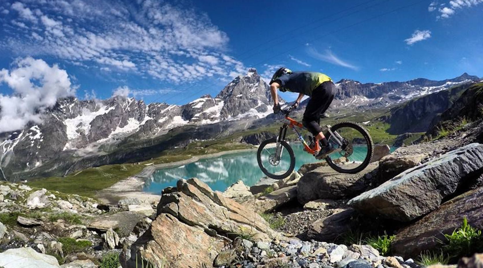 A cyclist downhill mountain biking in Cervinia, with the famous Matterhorn in the background.