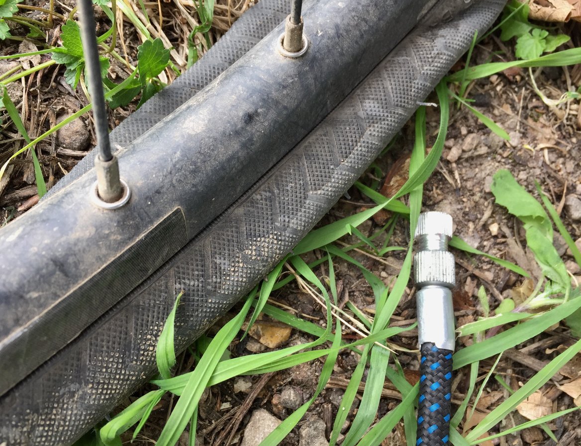 Close up of a punctured bicycle tyre, with a bike pump next to it.