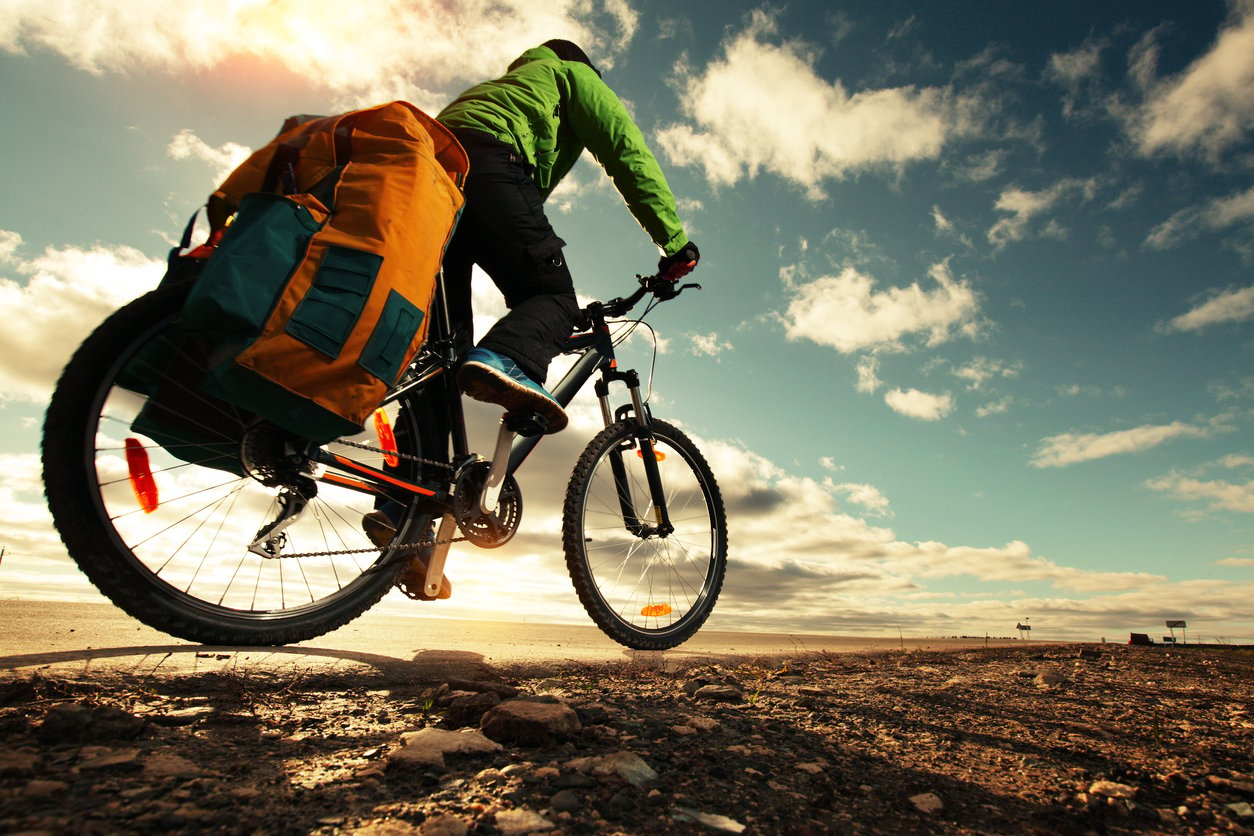 A cycle tourist riding along a rocky road at sunset