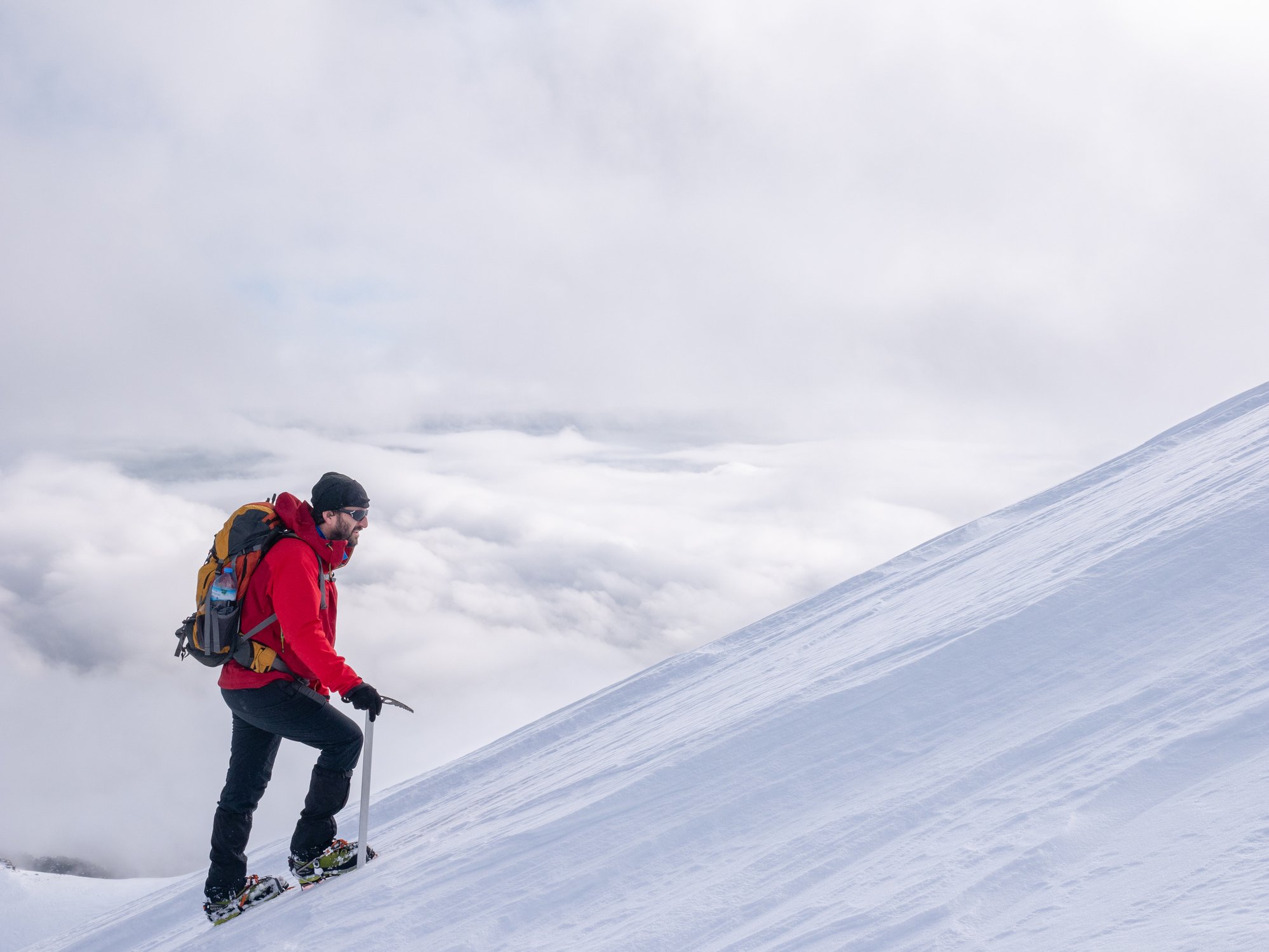 A male mountaineer climbing while wearing crampons