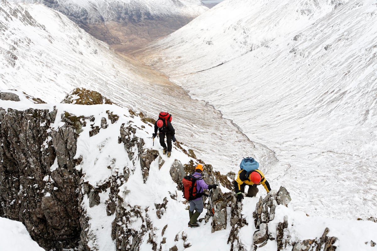 Climbers negotiating a snow-covered ridge in the Scottish Highlands