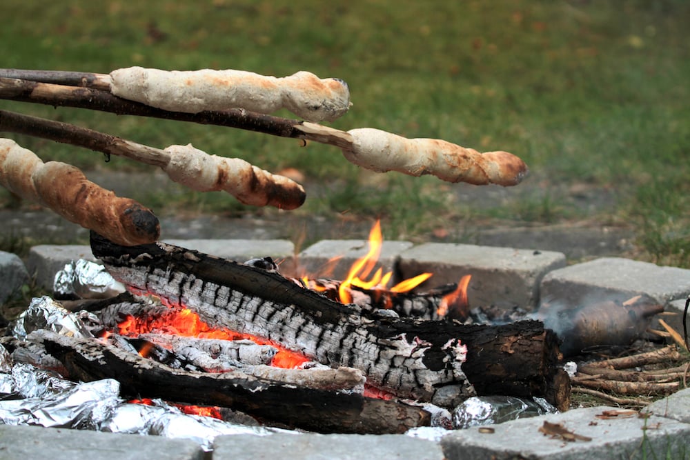 Cooking dampers (bread dough on a stick) over the campfire.