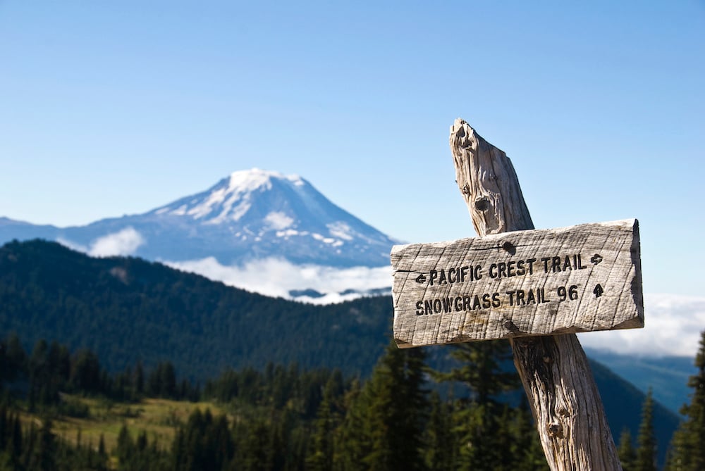 A sign for the Pacific Crest Trail with Mount Adams in the background.