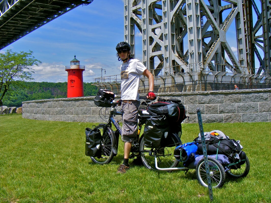 Leon McCarron posing next to bike and fully loaded trailer before beginning his cycle tour across North America