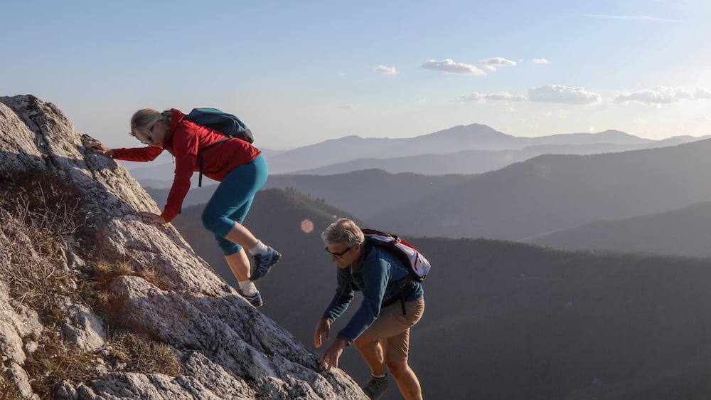 Climbers using both hands and feet to ascend a rocky ridgeline - a classic scrambling scene.