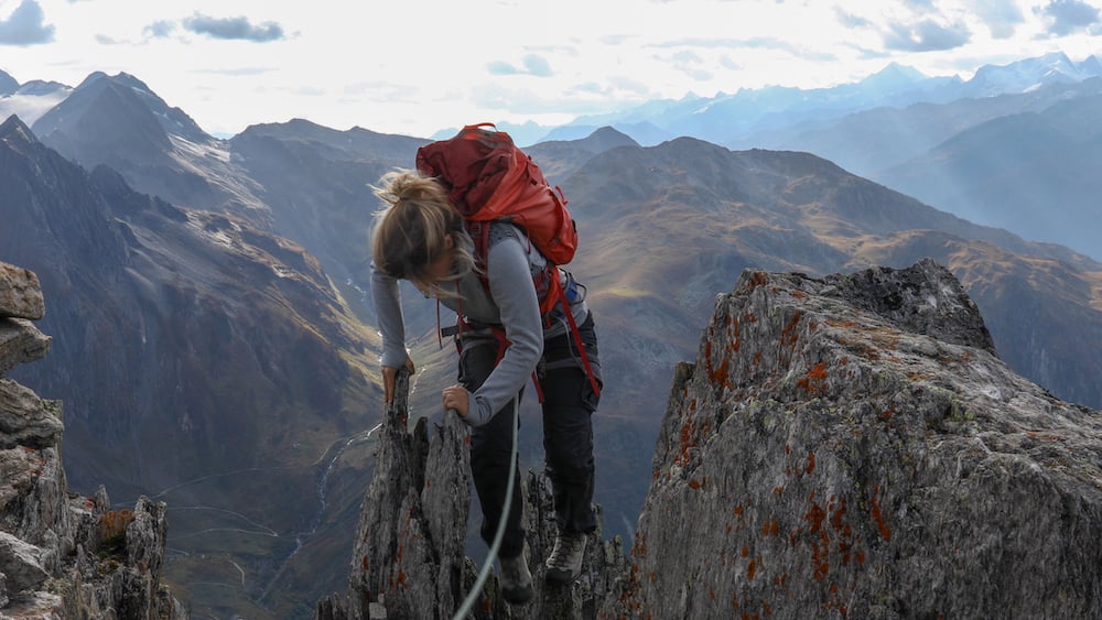 A woman tackling a grade three scramble with a rope for protection.