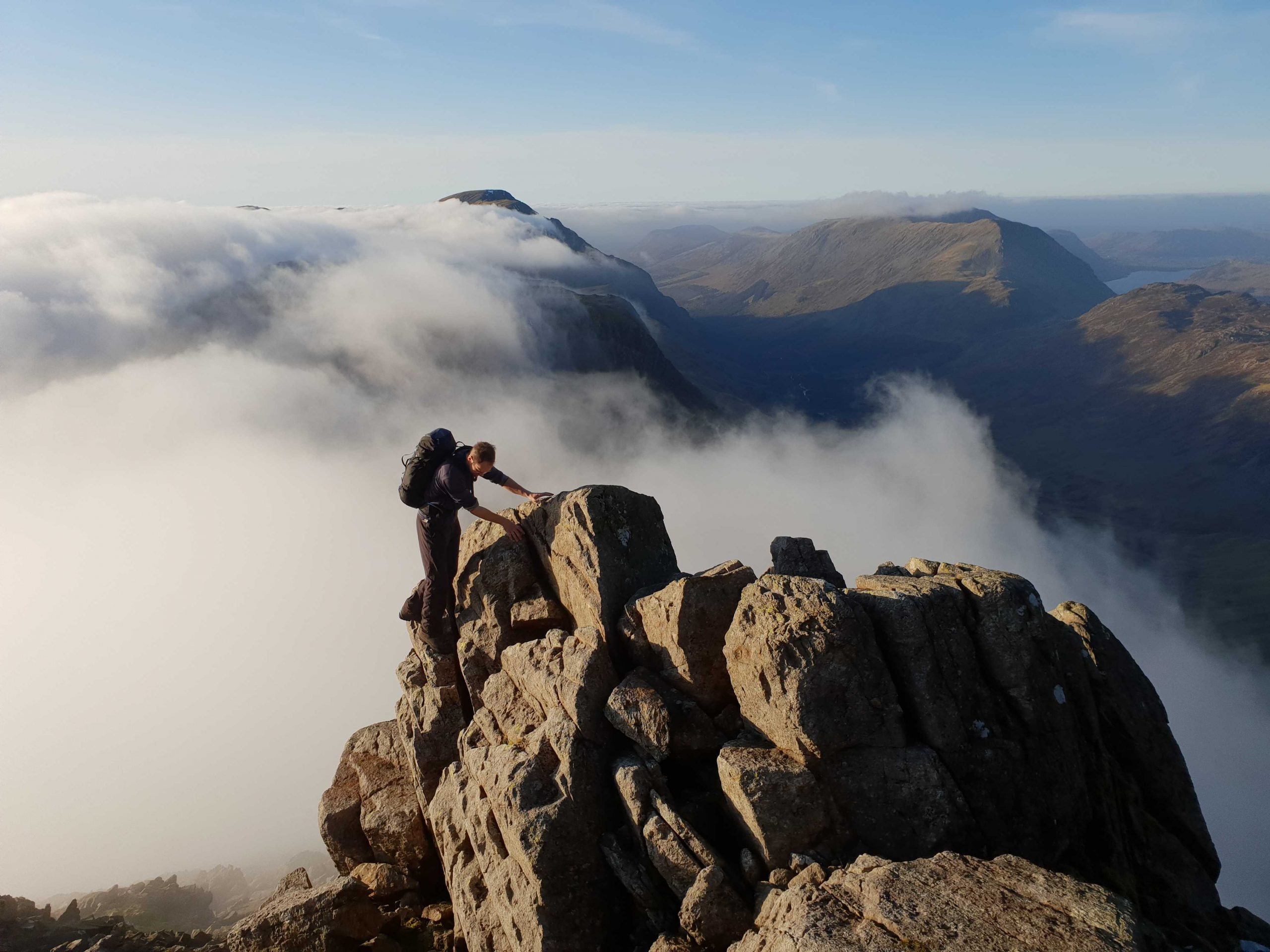 A male hiker scrambling up Great Gable, a Wainwright in the Lake District.