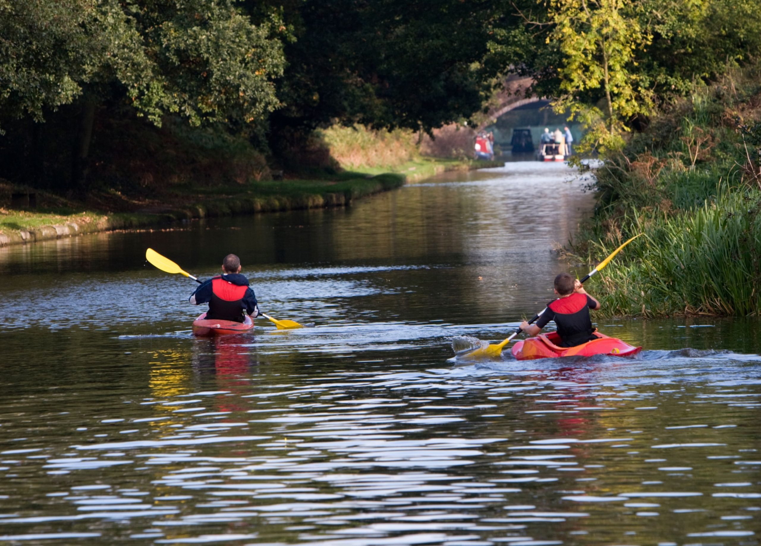 Two kayakers paddle down a river in the UK