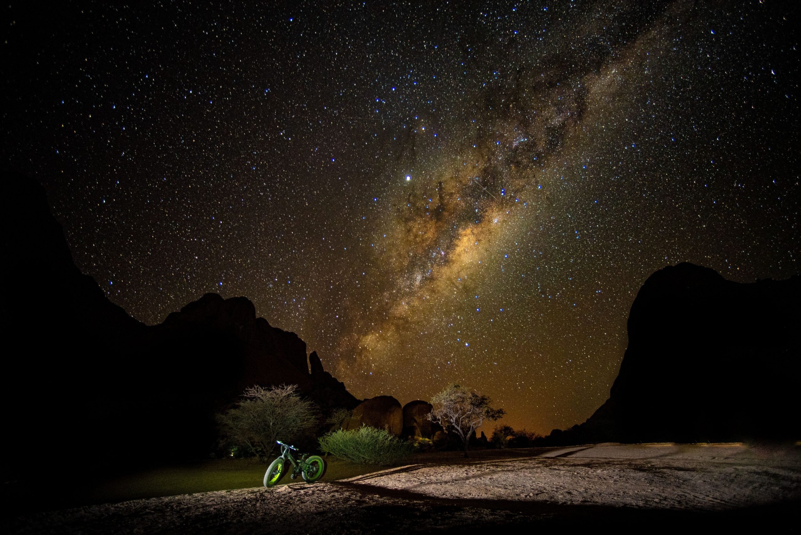 A bike in the Namib Desert, below a starry night sky.
