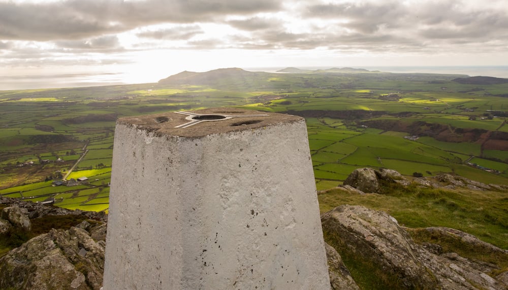A triangulation point and a view of the surrounding hills and sea.