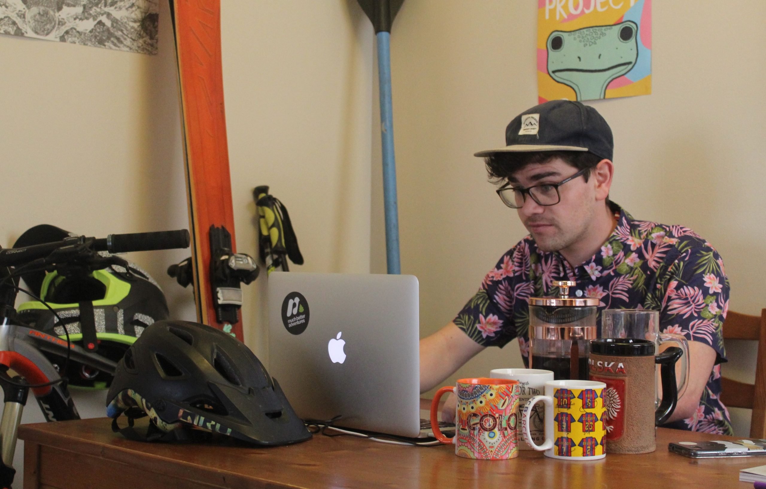 A man on his laptop, surrounded by outdoor gear.