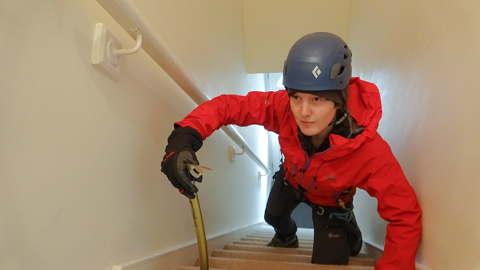 A woman dressed as a mountaineer climbing the stairs in her house
