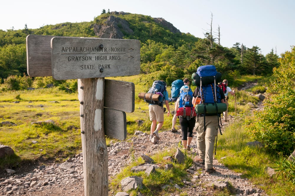 Hikers on the Appalachian Trail, with a waymarker in the foreground.