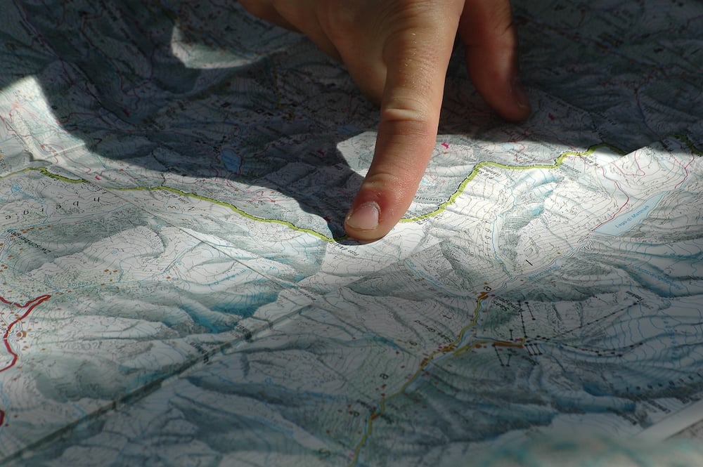 Someone's finger pinpoints a position on a map.