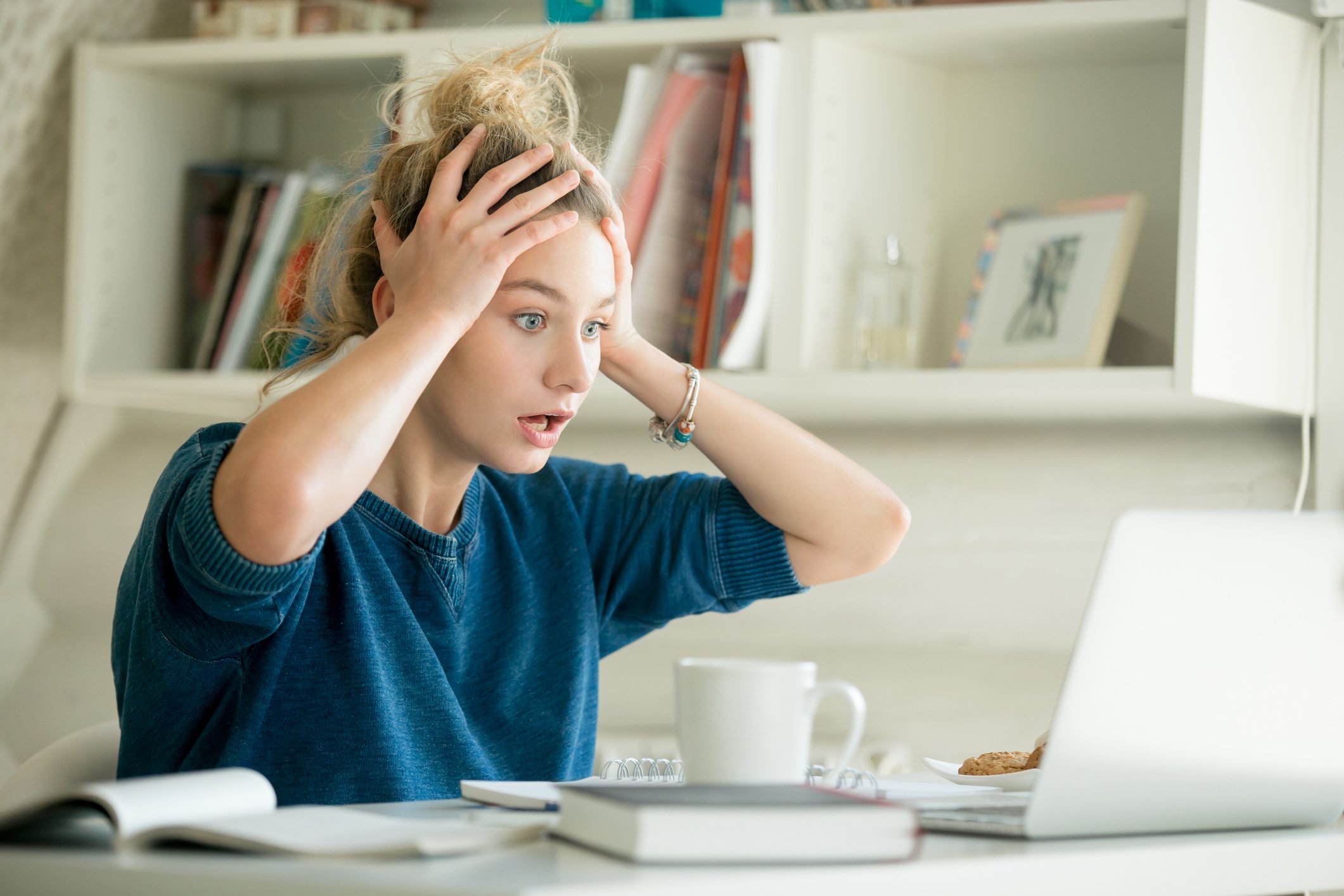 A woman looking in shock at a computer.