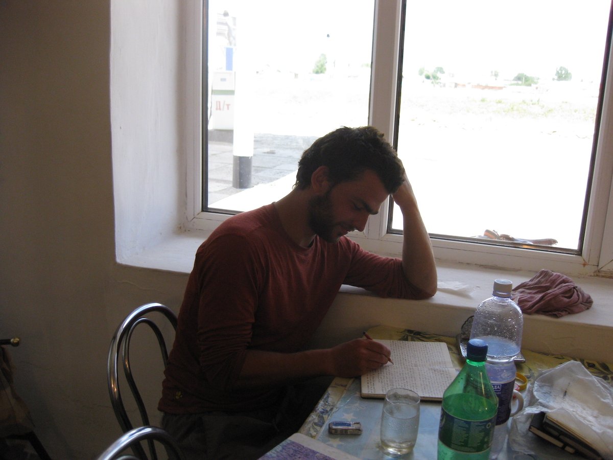 A man writes in a notebook in a cafe.