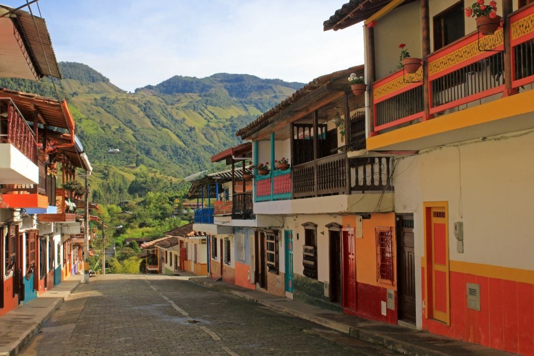 A colourful street in Medellín with the mountains behind.