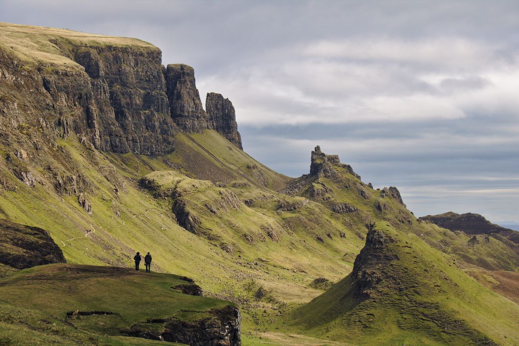 Two hikers looking out at the Isle of Skye's volcanic landscape.