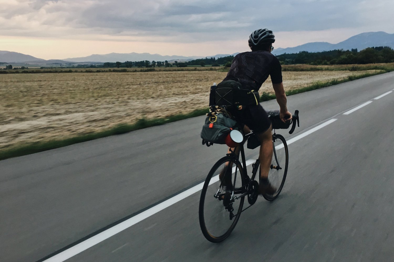 A cyclist rides into the horizon on a main road.