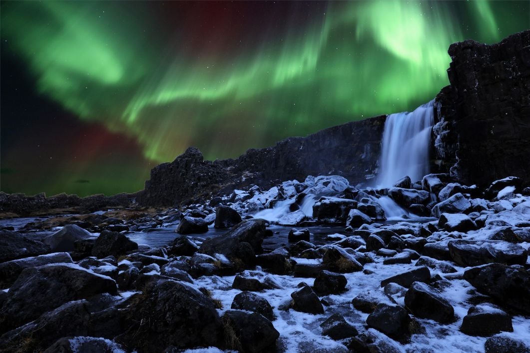 Northern Lights shining over Oxararfoss waterfall in Thingvellir National Park