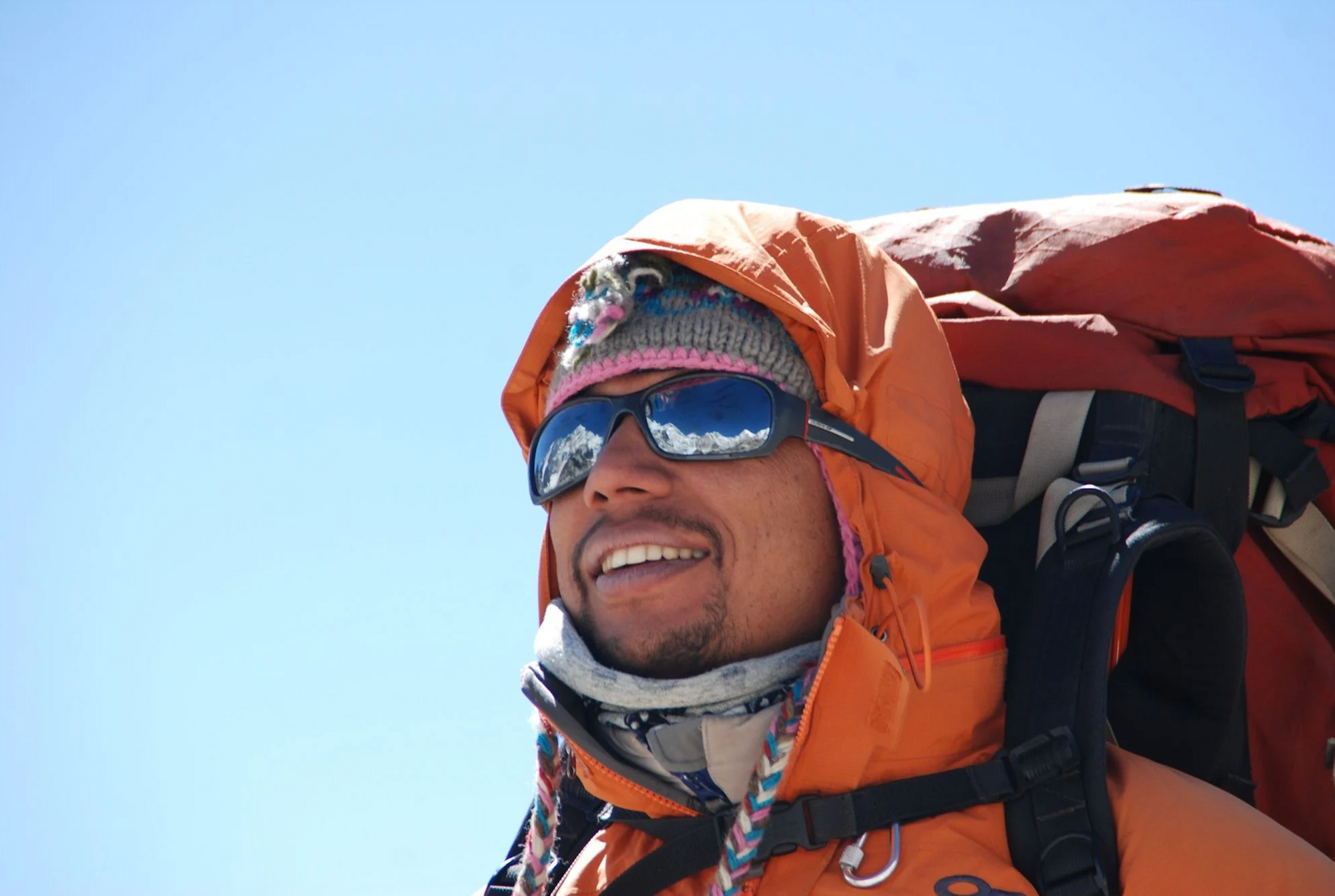 A hiker or mountaineer looks out on an adventurous mountain landscape.