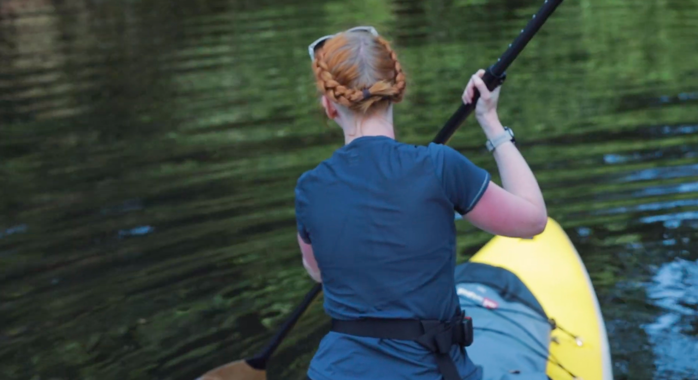 A woman on a stand-up paddleboard in a river.