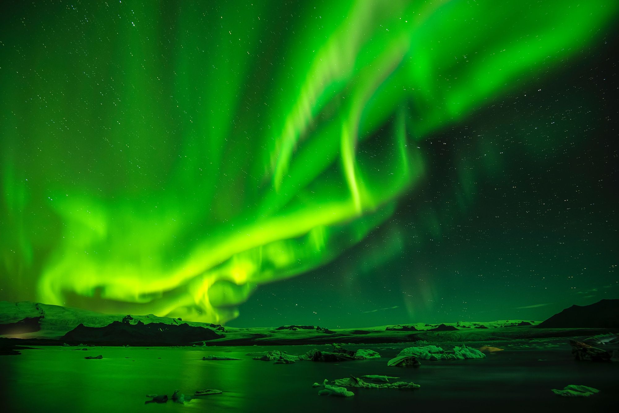 The northern lights, green aurora shining over a lake of icebergs