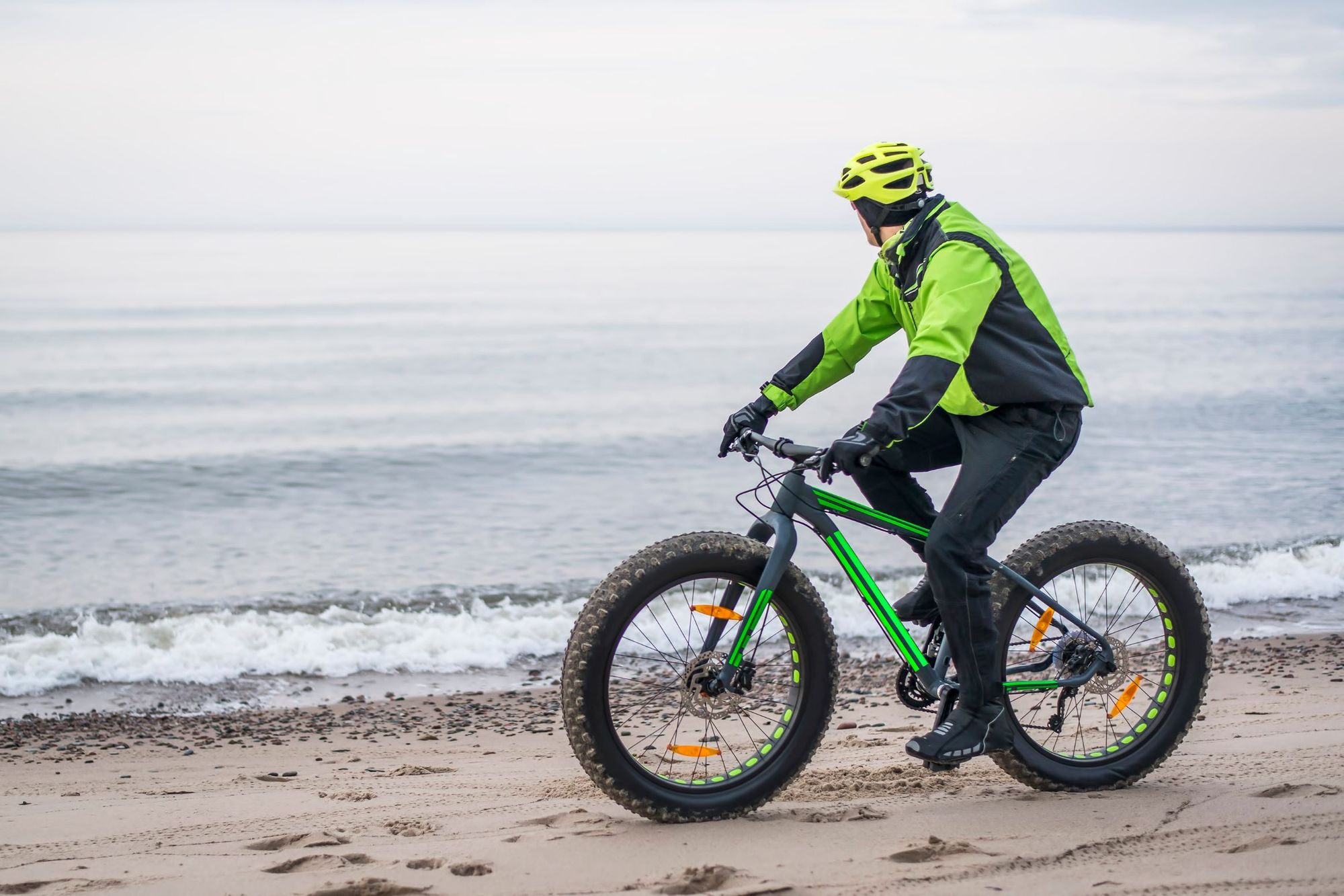 Male rider on a fatbike, riding on a beach.