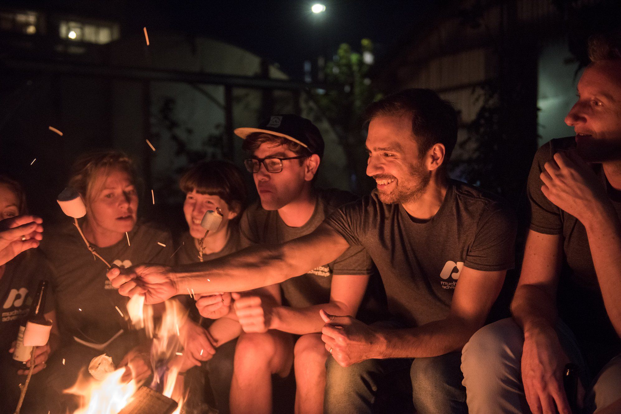 Young people toasting marshmallows on the campfire.