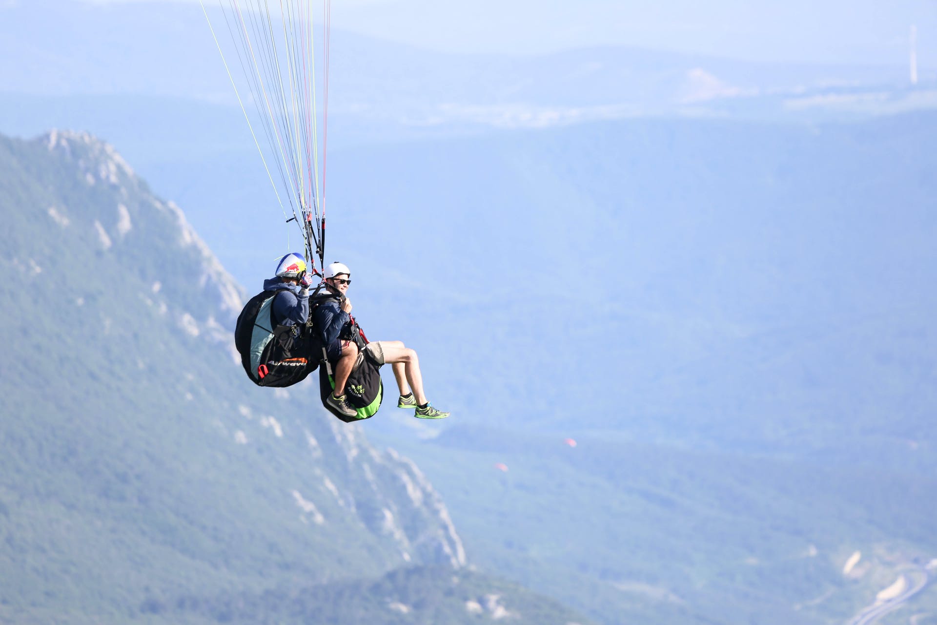 Two people on a tandem paraglide in Slovenia, floating over the mountains of Ajdovščina 