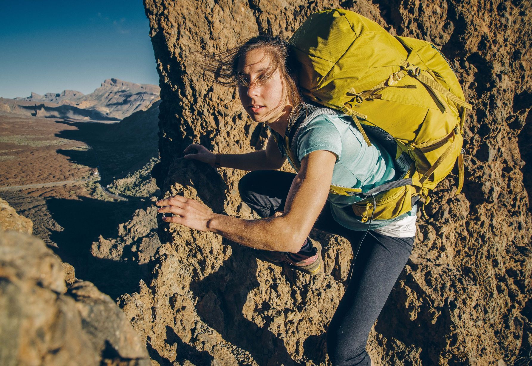 A woman climbs a rock in the mountains of Tenerife.