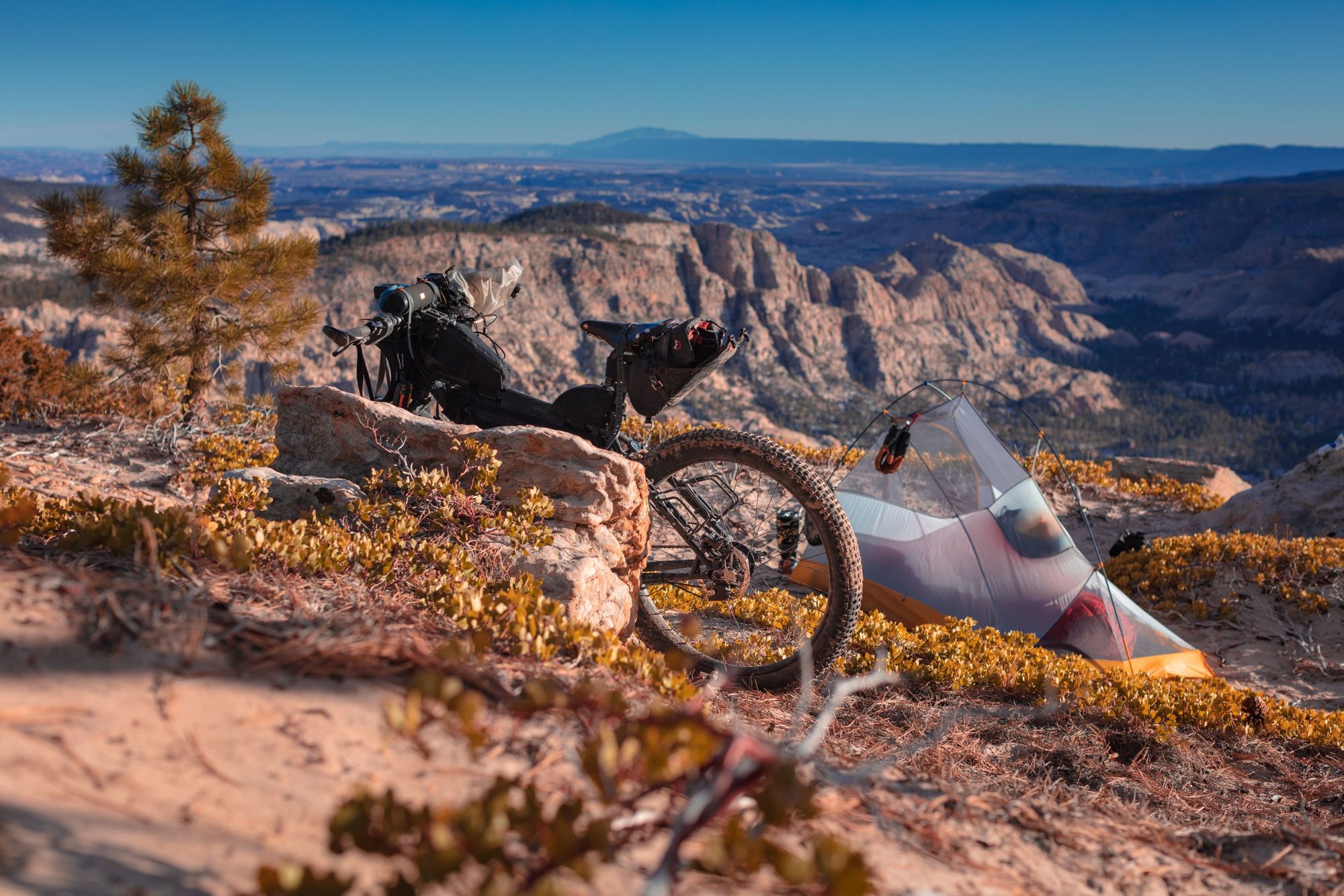 A bike and tent, with mountains in the background.