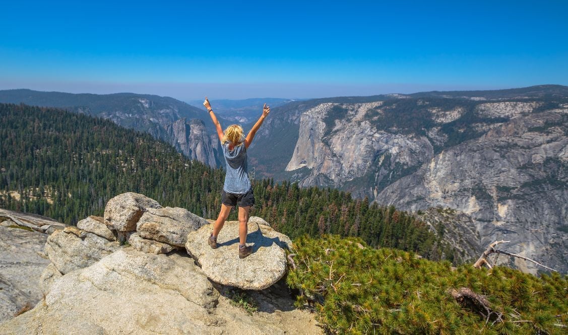 A woman hiker at the summit of Sentinel Dome, in Yosemite National Park.