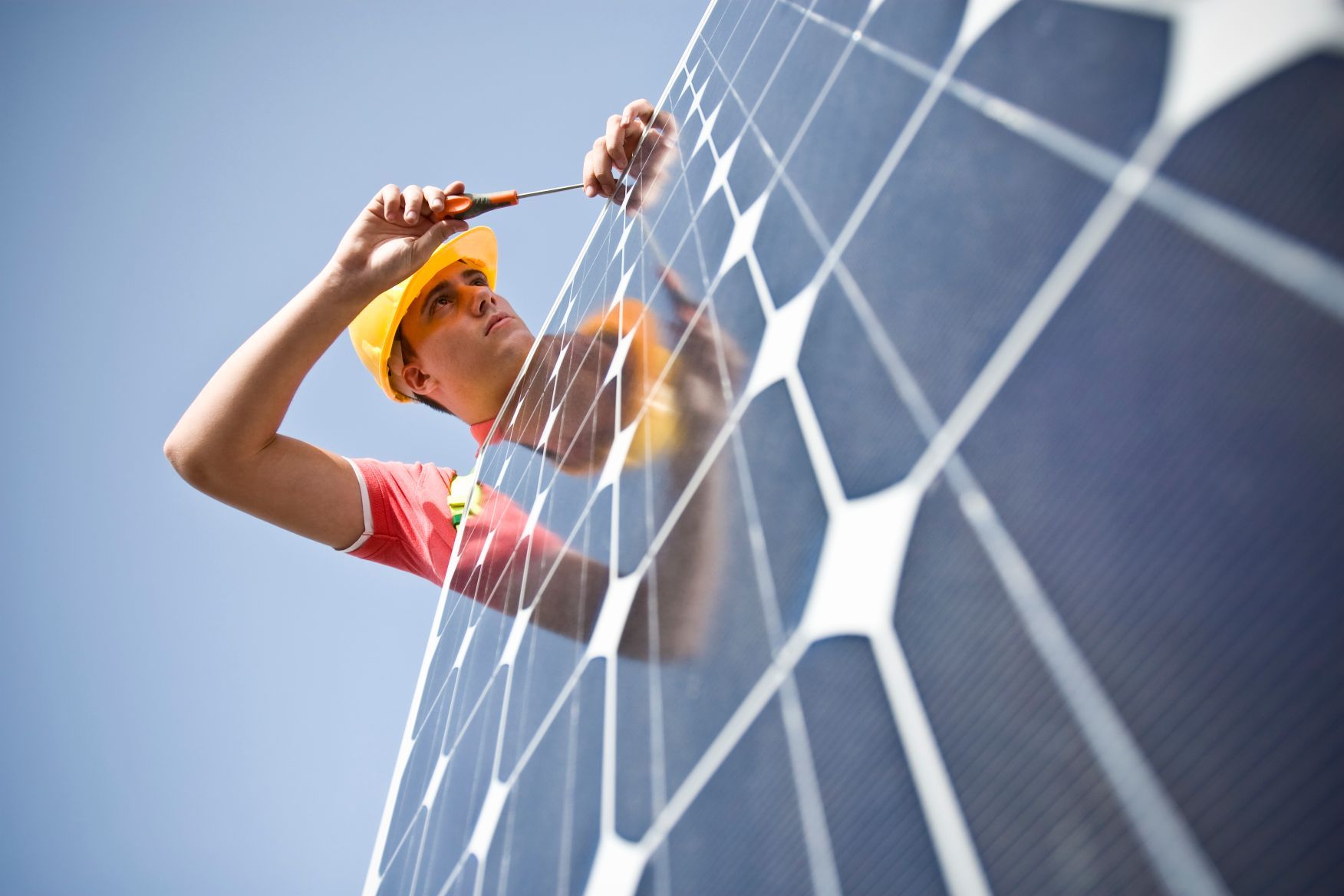 A workman installs solar panels on a building.