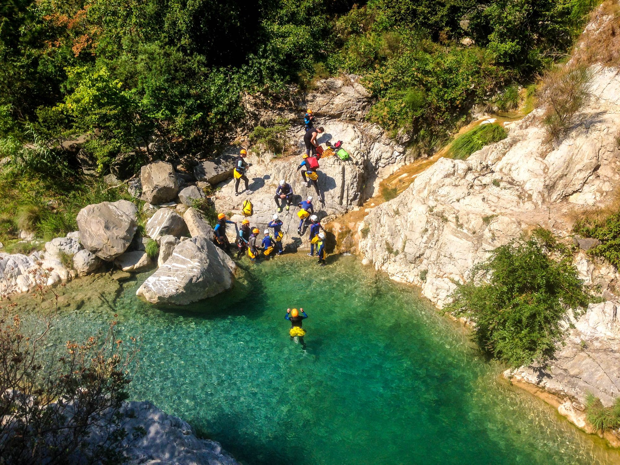 A coasteering team regroups after a successful outing, with turquoise water and sun-hit rocks.